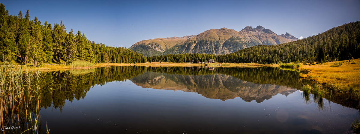 Stazersee mit spiegelglatter Wasseroberfläche, umgeben von Bergwäldern und Alpengipfeln im Oberengadin, Graubünden Schweiz – Jan Geerk Fotograf Basel