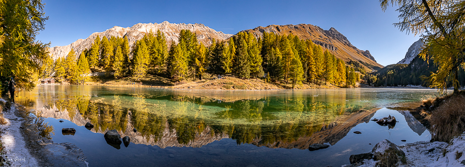 Alpiner See mit Lärchenwäldern in Herbstfarben, spiegelglatte Wasseroberfläche, Bergpanorama Graubünden Schweiz – Jan Geerk Fotograf Basel