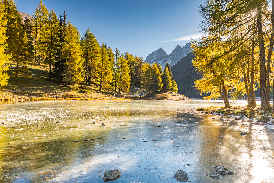 Gefrorener Bergsee mit goldenen Lärchen im Herbst, Graubünden Schweiz – Jan Geerk Fotograf Basel