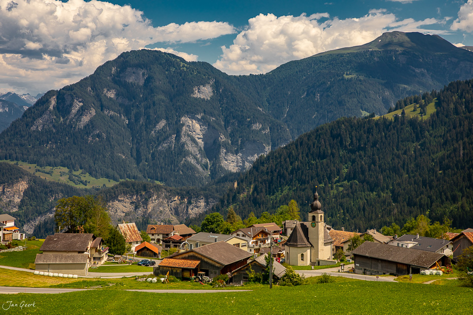 Alpendorf mit Kirche, Wiesen und Bergen im Sommer in Graubünden Schweiz – Jan Geerk Fotograf Basel