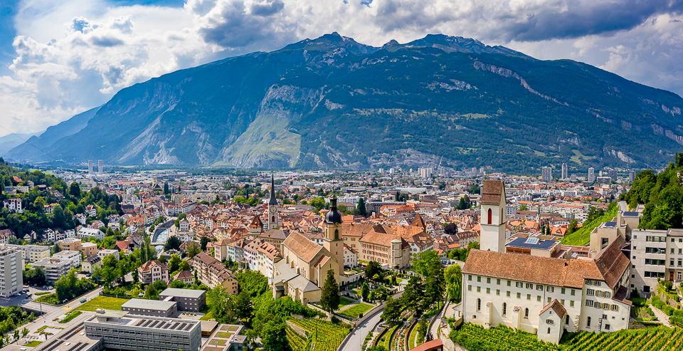 Luftaufnahme der Alpenstadt Chur mit Berge im Hintergrund, sonnige Sommerstimmung Graubünden Schweiz – Jan Geerk Fotograf Basel