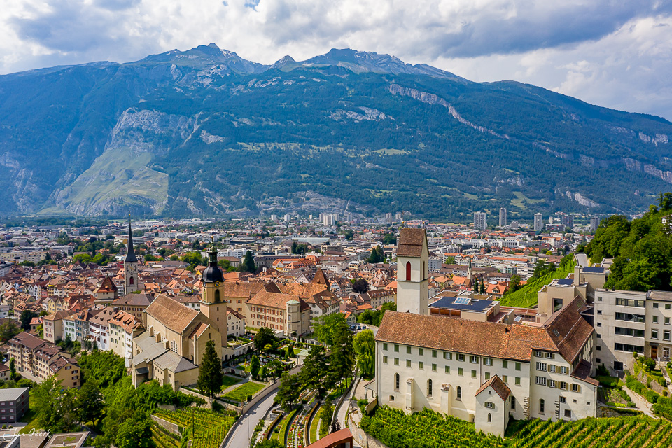 Luftaufnahme von Chur mit Kirchen, Altstadtdächern und Rheintal unter blauem Himmel, Graubünden Schweiz – Jan Geerk Fotograf Basel