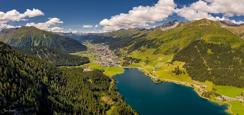 Luftaufnahme Davos mit türkisblauem See, grünen Alpen und Bergdorf im Sommer, Graubünden Schweiz – Jan Geerk Fotograf Basel