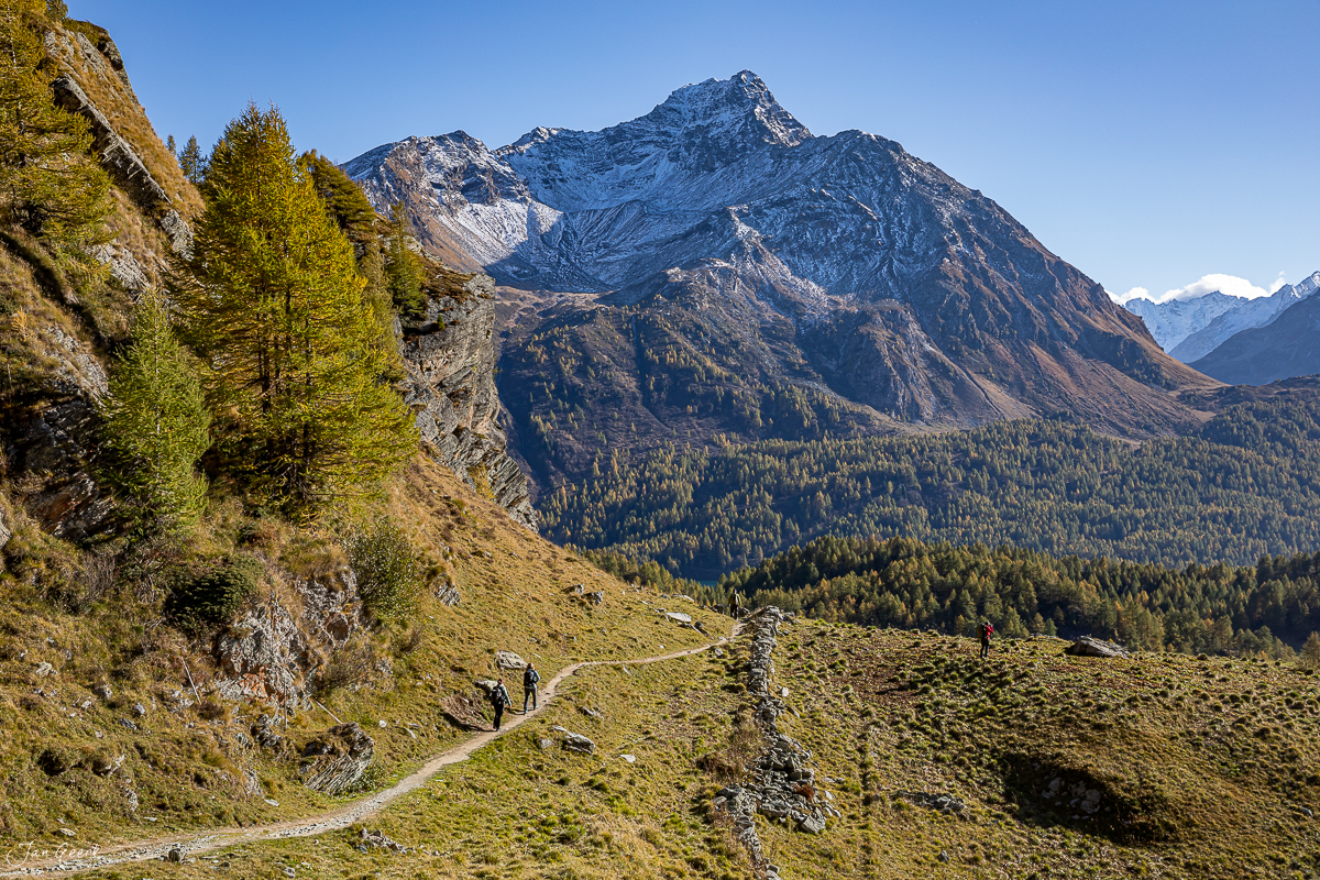 Wanderer auf Bergpfad mit Lärchen im Herbst, Engadin Graubünden Schweiz – Jan Geerk Fotograf Basel