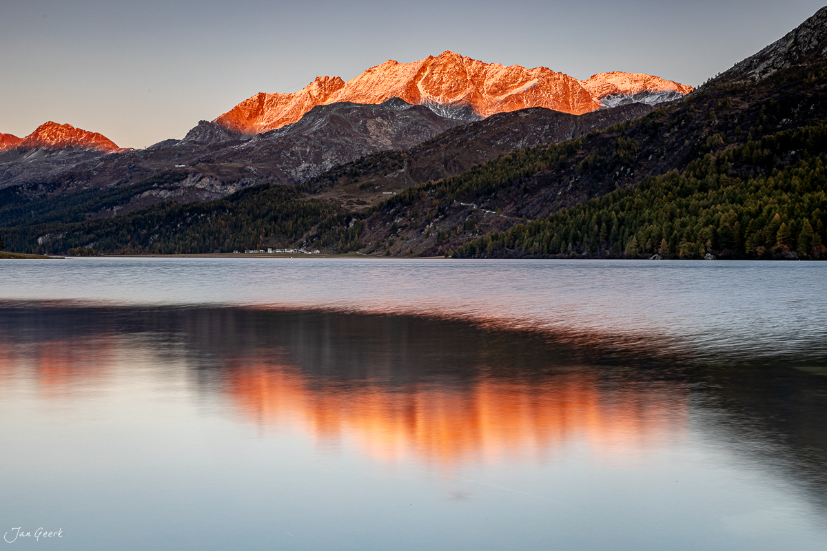 Alpengipfel mit Schnee spiegelt sich in glatter Seefläche bei Sonnenaufgang, Engadin Graubünden Schweiz – Jan Geerk Fotograf Basel
