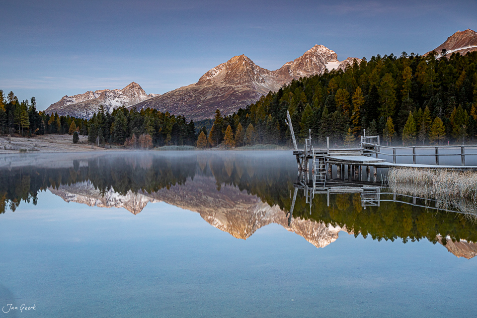 Spiegelglatter Bergsee mit schneebedeckten Gipfeln und Lärchenwäldern im Engadin Schweiz Jan Geerk Fotograf Basel