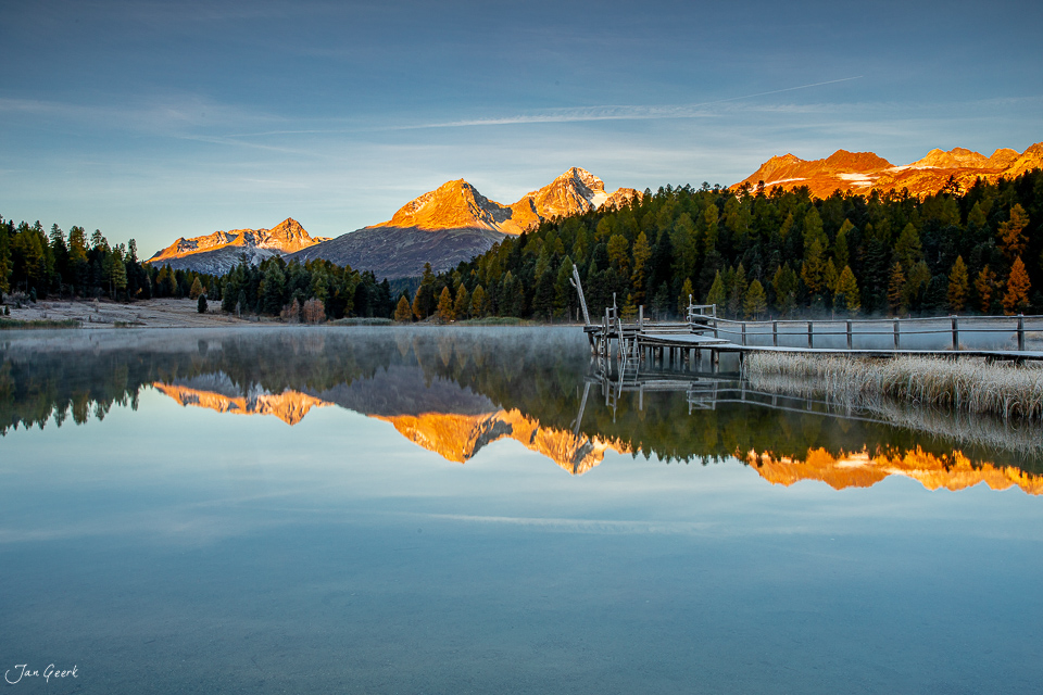 Spiegelung von schneebedeckten Bergen im See mit Steg und Lärchenwäldern, Herbst Engadin Schweiz – Jan Geerk Fotograf Basel