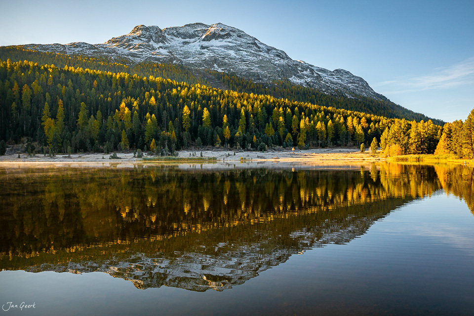 Spiegelglatter Stazersee mit herbstlich gefärbten Lärchen und schneebedecktem Berg, Engadin Graubünden Schweiz – Jan Geerk Fotograf Basel
