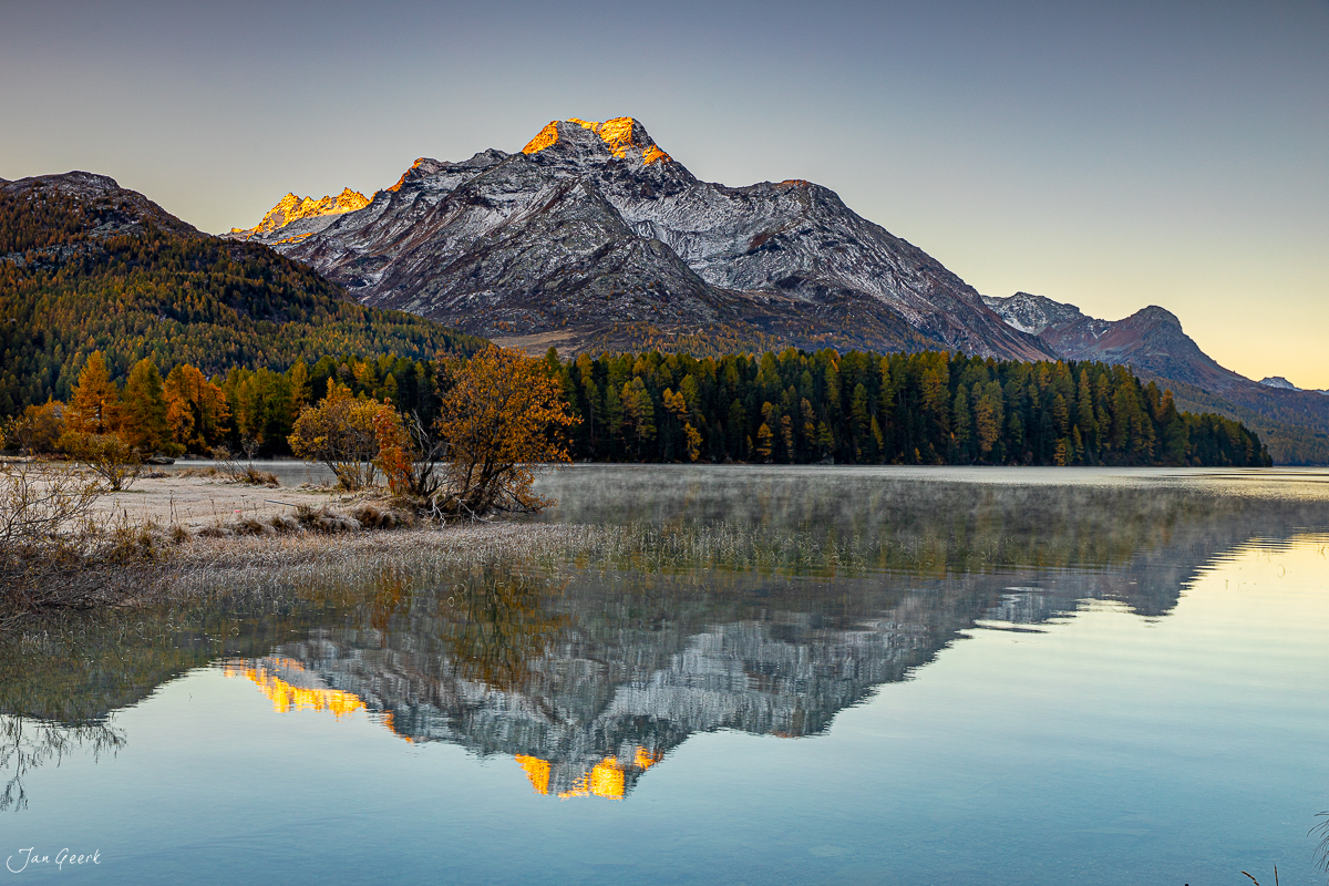 Spiegelung des verschneiten Bergs im Silsersee, Herbstwald, Engadin Graubünden Schweiz – Jan Geerk Fotograf Basel