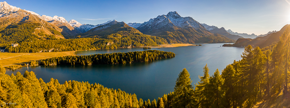 Alpiner See mit Lärchenwäldern im Herbst, schneebedeckte Berge, goldenes Licht, Graubünden Schweiz – Jan Geerk Fotograf Basel