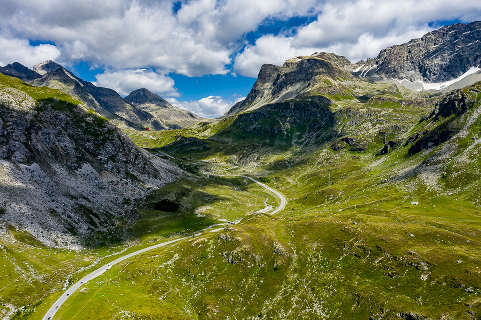 Luftaufnahme Julierpass mit Serpentinenstrasse, grüne Alpenweiden und Bergketten, Sommerlichtstimmung Graubünden Schweiz – Jan Geerk Fotograf Basel