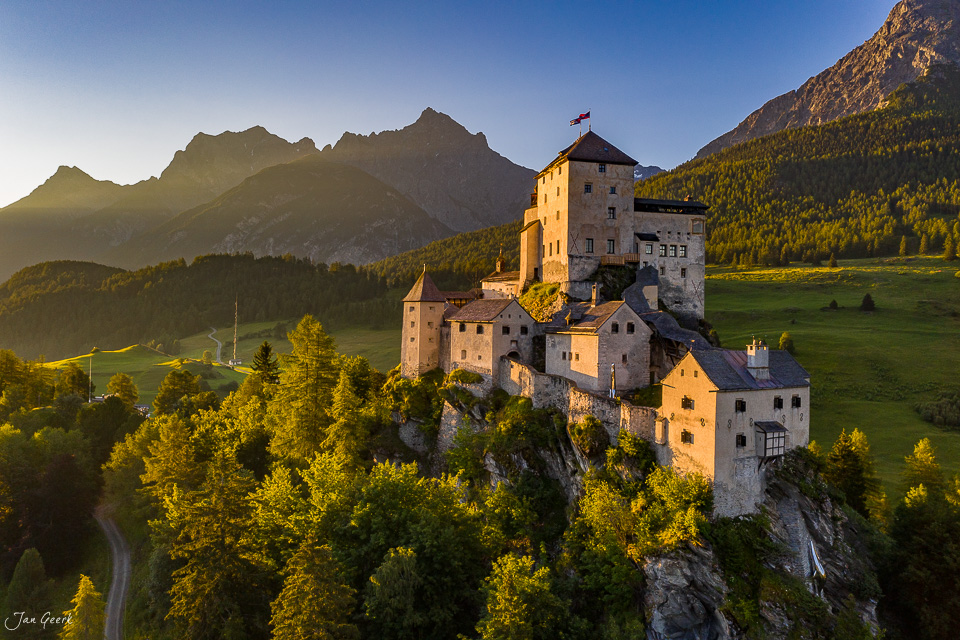 Schloss Tarasp auf Felsvorsprung, Engadin-Tal mit Bergen im Gegenlicht, Sommerstimmung Graubünden Schweiz – Jan Geerk Fotograf Basel