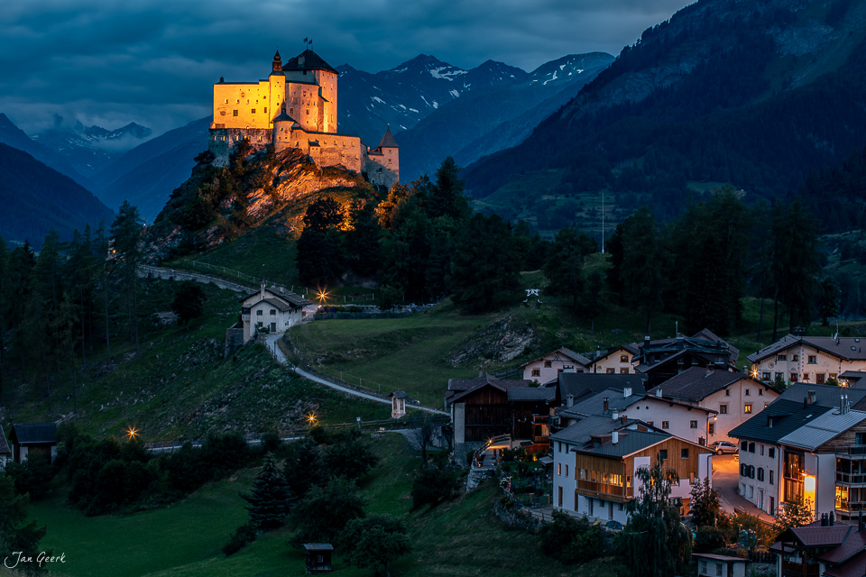 Schloss Tarasp beleuchtet bei Dämmerung mit Bergdorf im Unterengadin, Graubünden Schweiz – Jan Geerk Fotograf Basel