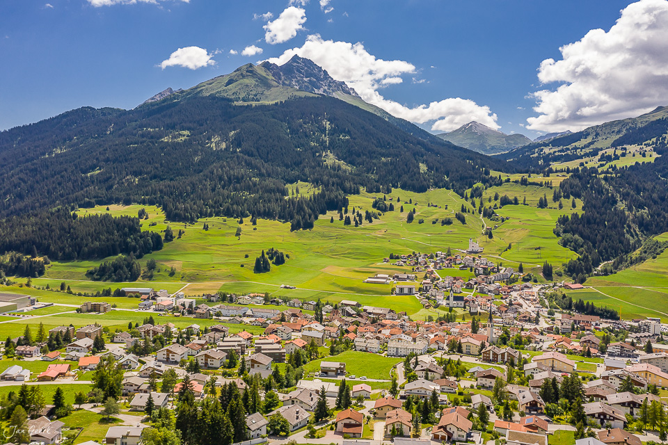 Luftaufnahme des malerischen Dorfes Savognin mit grünen Alpenwiesen und Bergen im Sommer, Graubünden Schweiz – Jan Geerk Fotograf Basel