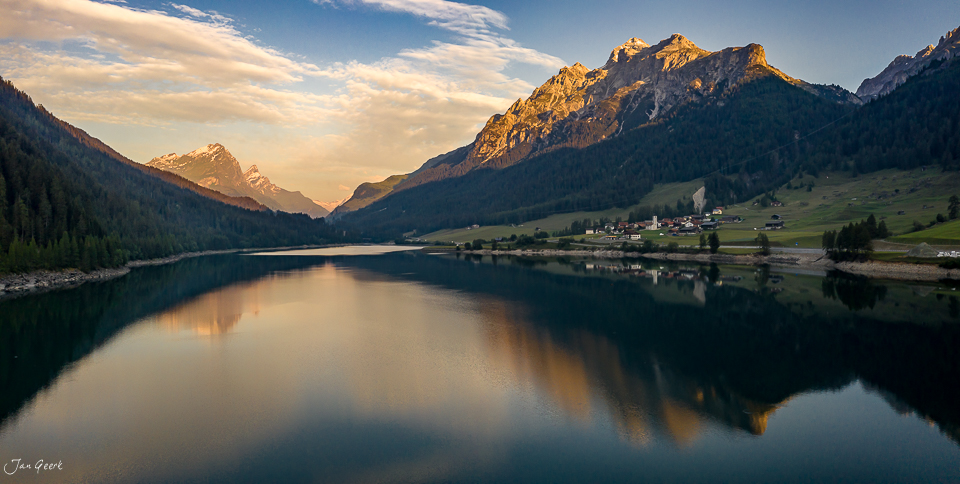 Spiegelglatter Bergsee bei Sufers mit schneebedeckten Alpengipfeln in goldener Sommerlicht-Stimmung, Graubünden Schweiz – Jan Geerk Fotograf Basel