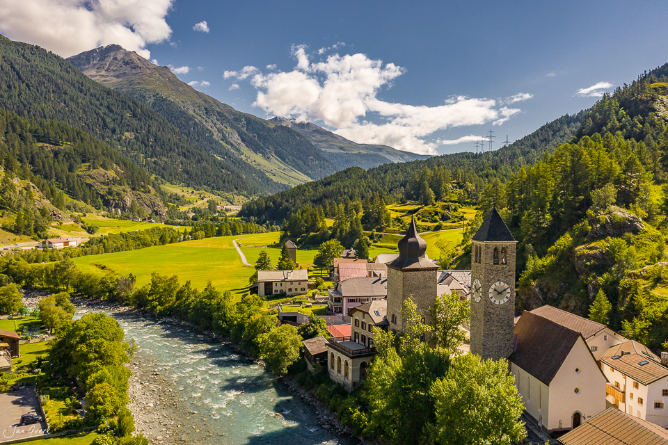 Luftaufnahme Susch mit Kirche, Fluss und Bergen im Sommer in Graubünden Schweiz – Jan Geerk Fotograf Basel