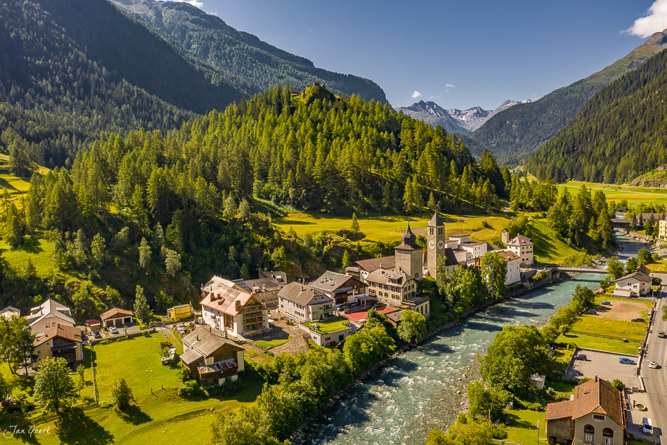 Luftaufnahme des Dorfes Susch im Unterengadin mit Kirche, Fluss und Bergwäldern bei Sommerlicht – Jan Geerk Fotograf Basel