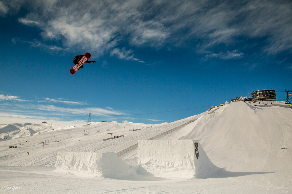 Snowboarder springt über Halfpipe in Laax, Schnee und blauer Himmel, Schweiz – Jan Geerk Fotograf Basel