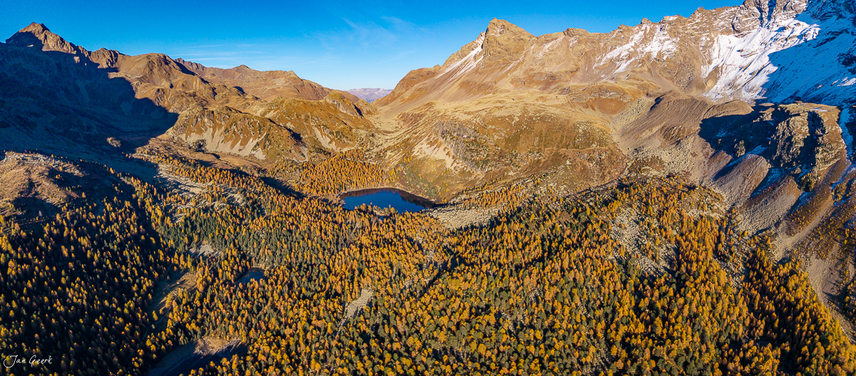 Herbstliche Luftaufnahme des Lago di Saoseo mit goldenen Lärchen und schneebedeckten Bergen in Graubünden Schweiz – Jan Geerk Fotograf Basel