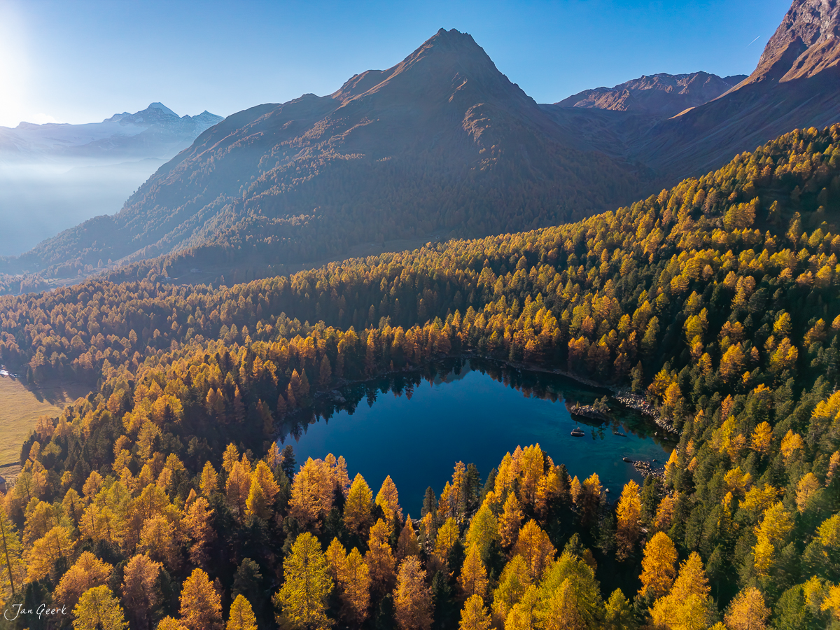 Bergsee mit goldenen Lärchen im Herbst, umgeben von Alpengipfeln in der Schweiz – Jan Geerk Fotograf Basel