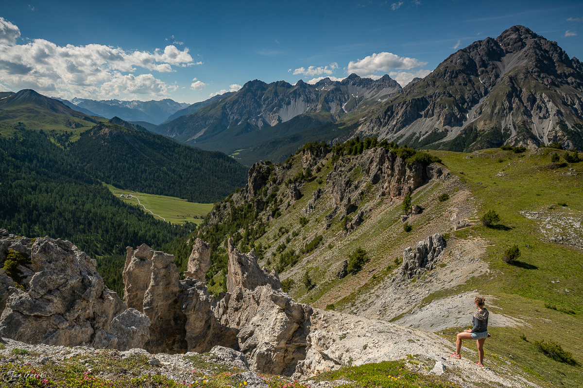 Wanderin auf Alpenwiese mit Blick ins Engadin, Sommerliche Berglandschaft mit Felsformationen, Graubünden Schweiz – Jan Geerk Fotograf Basel
