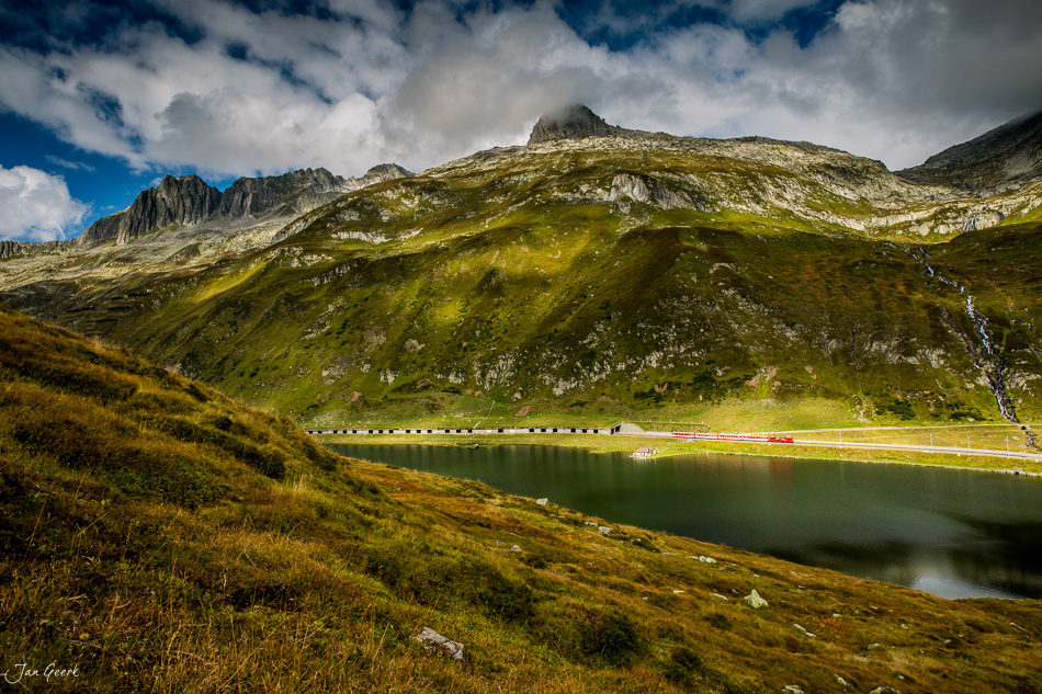 Alpensee mit Zuggleisen und grüner Berglandschaft Oberalp Graubünden Schweiz Jan Geerk Fotograf Basel