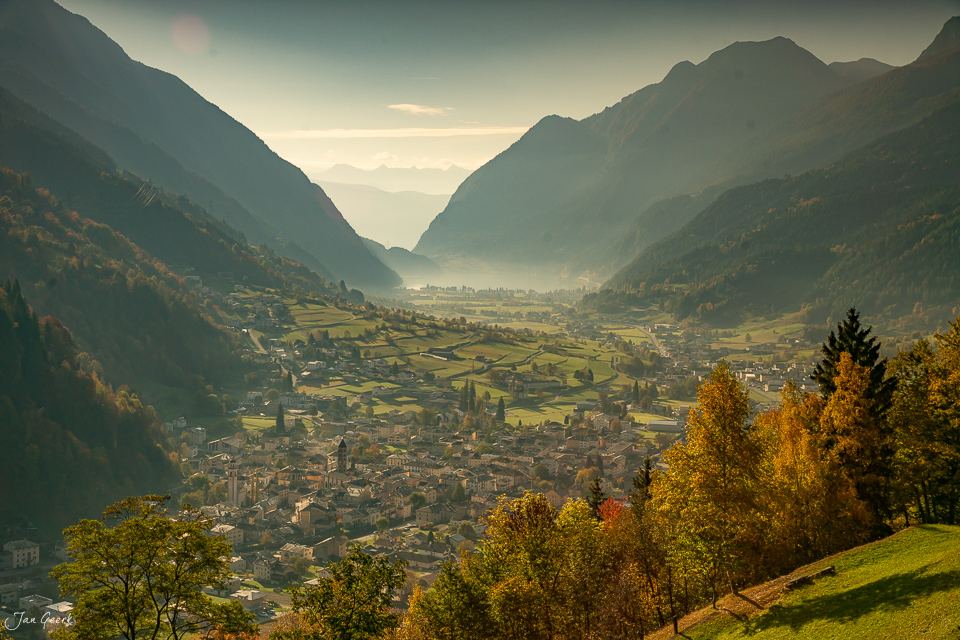 Herbstliches Dorf Poschiavo im Tal mit Bergen und Laubwald, goldene Kantlicht-Stimmung, Graubünden Schweiz – Jan Geerk Fotograf Basel