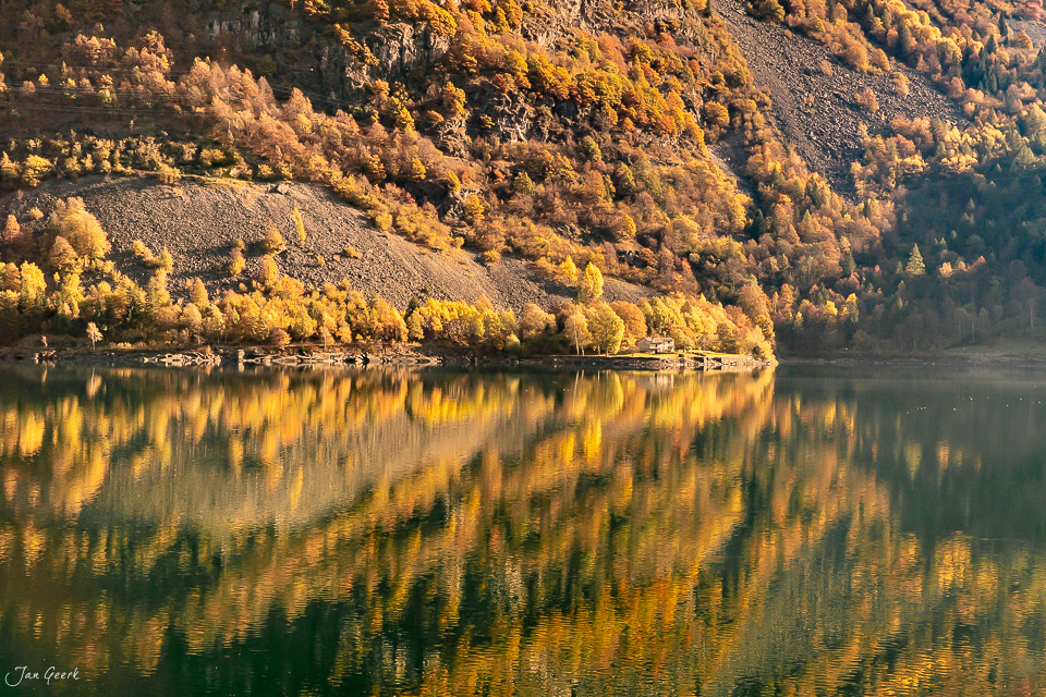 Herbstliche Spiegelung des Lago di Poschiavo mit goldenen Lärchen in Graubünden Schweiz – Jan Geerk Fotograf Basel