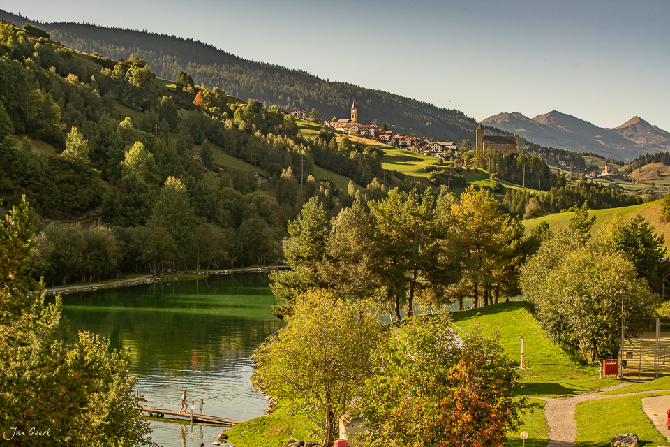 Dorf Riom mit Kirche, herbstlich beleuchtete Landschaft, Flusstal mit Wald, Graubünden Schweiz – Jan Geerk Fotograf Basel