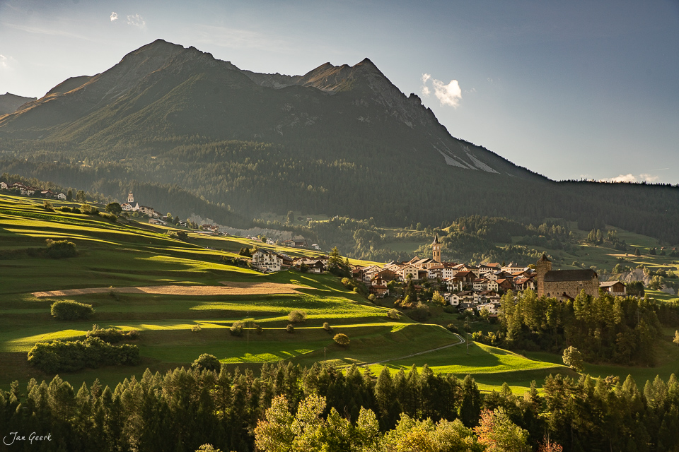 Dorf Savognin mit Kirche und Schloss in grüner Berglandschaft, Herbstlicht, Graubünden Schweiz – Jan Geerk Fotograf Basel