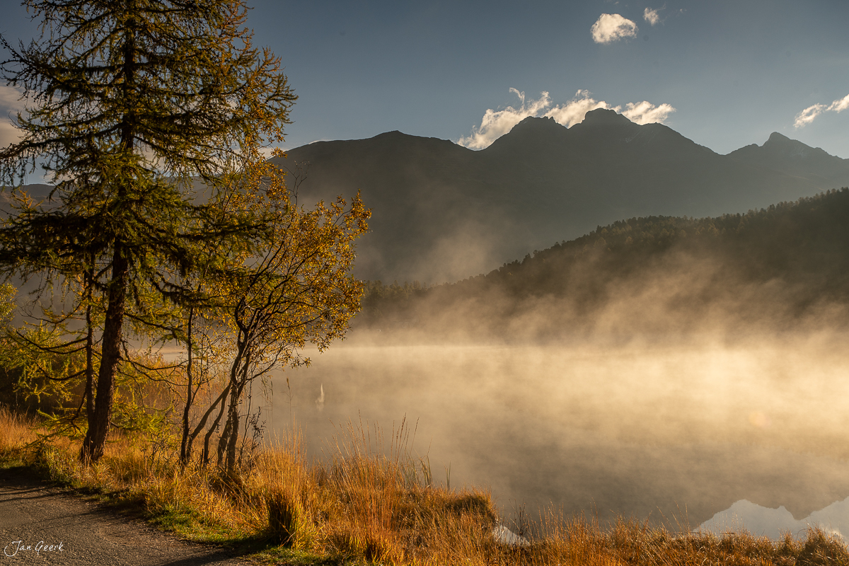 Herbstliche Lärchen am Stazersee mit Nebel und Bergen, Oberengadin Graubünden Schweiz – Jan Geerk Fotograf Basel