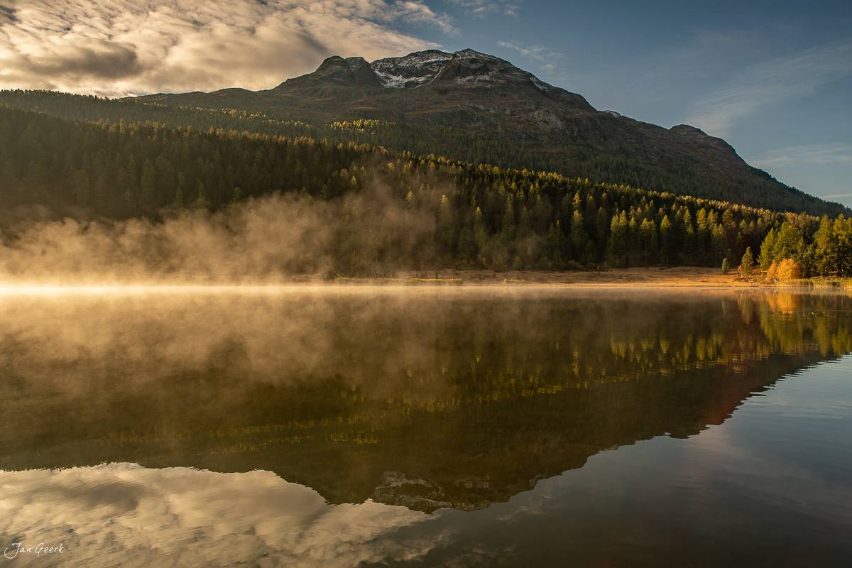 Bergsee mit Herbstwald und schneebedecktem Berg im Morgennebel, Engadin Graubünden Schweiz – Jan Geerk Fotograf Basel