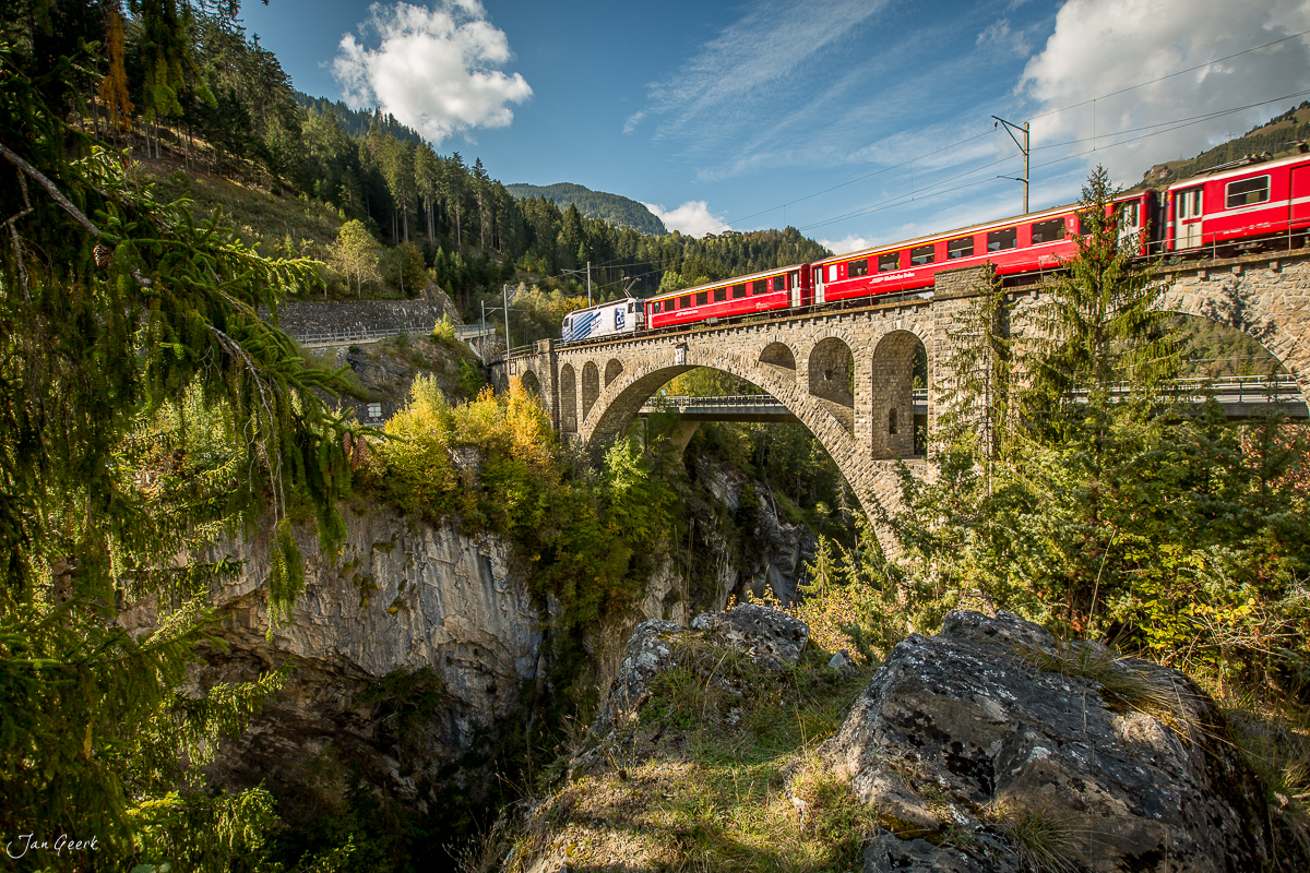 Rote Zahnradbahn überquert imposante Steinbogenbrücke über Schlucht bei Solisbrücke, Graubünden Schweiz – Jan Geerk Fotograf Basel