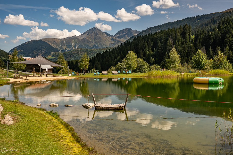 Bergsee mit Ruderbooten am Ufer, grüne Berglandschaft in Sedrun im Sommer, Graubünden Schweiz – Jan Geerk Fotograf Basel