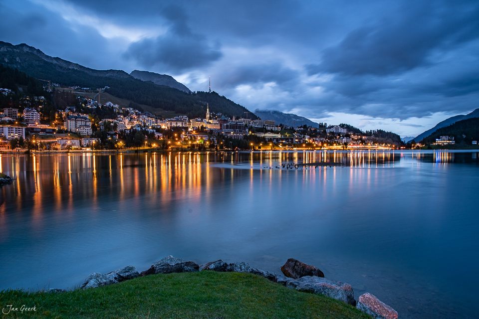 Seeufer mit Steinen, beleuchtete Stadt St. Moritz am Abend, Engadin Graubünden Schweiz – Jan Geerk Fotograf Basel