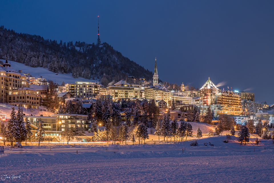 Verschneites Dorf St. Moritz in der Abenddämmerung mit beleuchteten Hotels und Kirche, Engadin Graubünden Schweiz – Jan Geerk Fotograf Basel