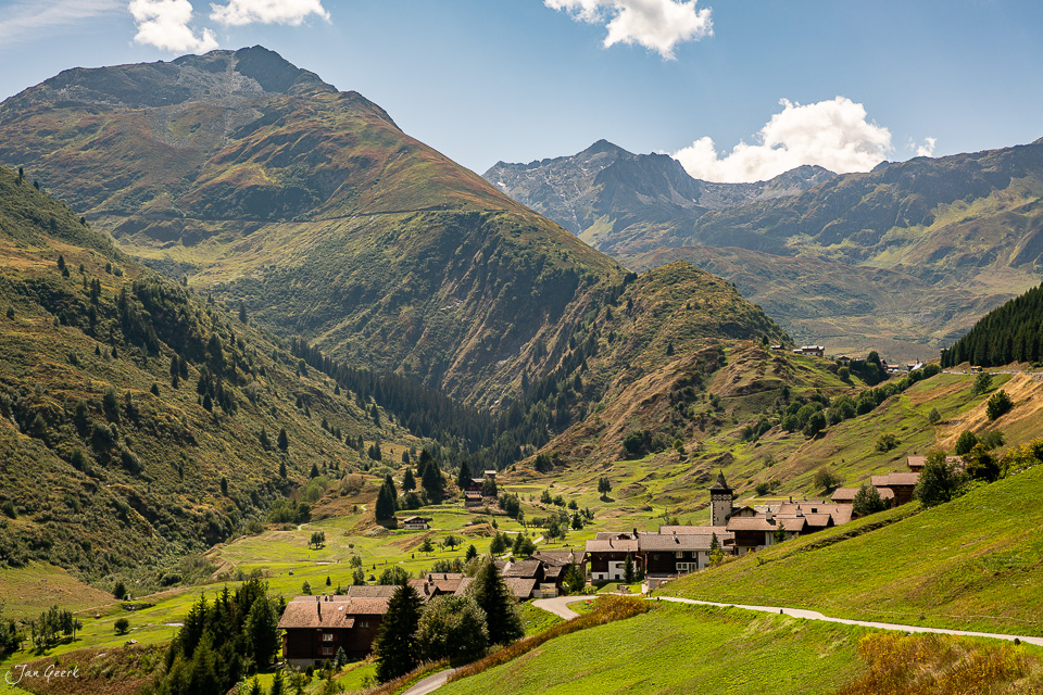 Alpendorf Tschamut mit Bergketten in Sommergrün, Kantlicht über Graubünden Schweiz – Jan Geerk Fotograf Basel