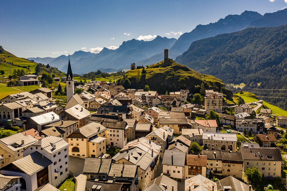Luftaufnahme des Dorfes Ardez im Unterengadin mit Kirchturm, Burgruine Tarasp und Bergpanorama im Sommer, Graubünden Schweiz – Jan Geerk Fotograf Basel