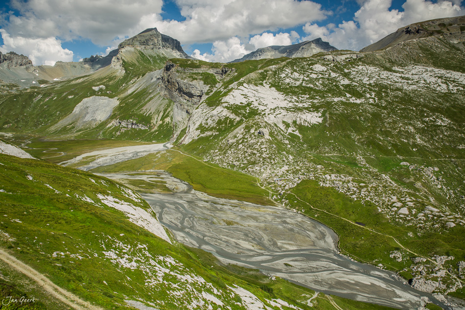 Berglandschaft Segnesboden mit Gebirgsbach, grüne Alpweiden und Felsmassive unter blauem Himmel in Graubünden Schweiz – Jan Geerk Fotograf Basel