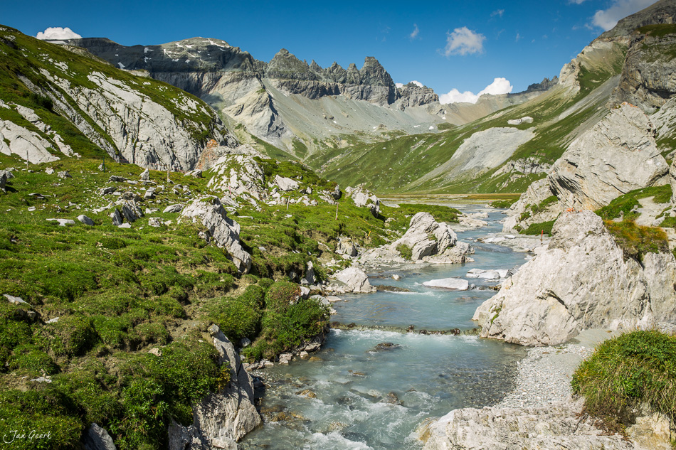 Bergbach im grünen Segnesboden unter Alpengipfeln, Sommerlandschaft in Graubünden Schweiz – Jan Geerk Fotograf Basel
