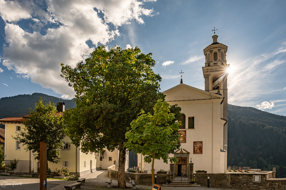 Kirche mit Glockenturm und altem Baum in Tinizong, Surses Graubünden, sonnig – Jan Geerk Fotograf Basel