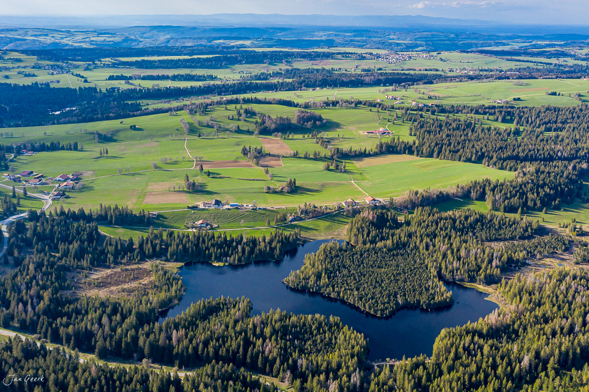 Luftaufnahme Étang de la Gruère mit Seen, Wäldern und Frühjahrslandschaft im Jura, Schweiz – Jan Geerk Fotograf Basel