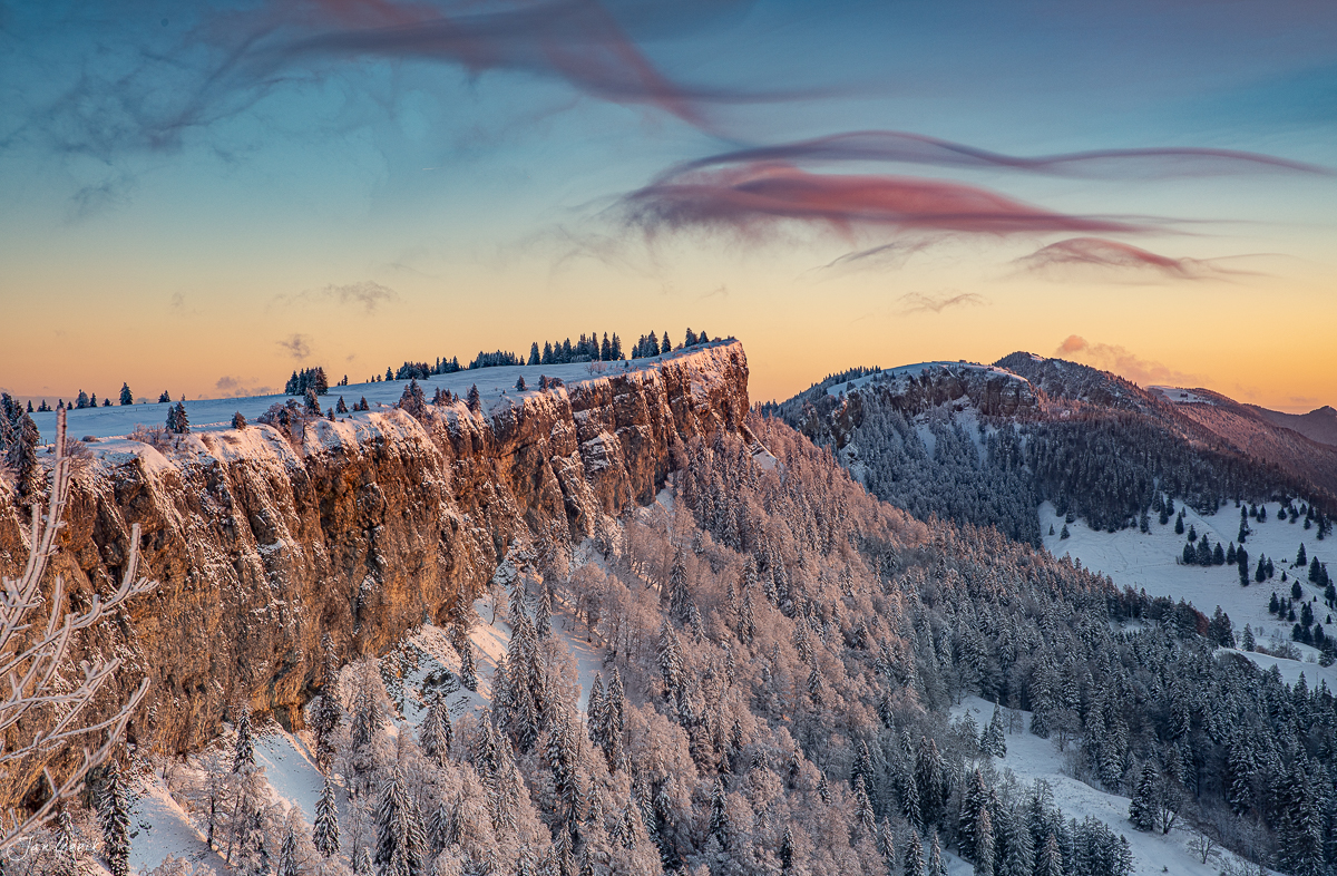 Schneebedeckte Felswand und Nadelwald bei Sonnenaufgang am Grenchenberg im Jura Schweiz – Jan Geerk Fotograf Basel