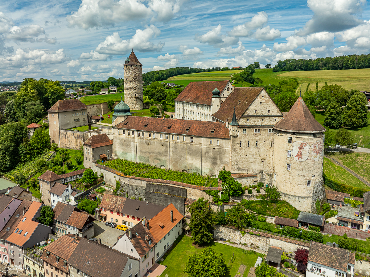 Schloss Porrentruy mit Wehrtürmen und Klostergebäuden im grünen Jura, Sommerluft mit Cumulus-Wolken, Schweiz – Jan Geerk Fotograf Basel