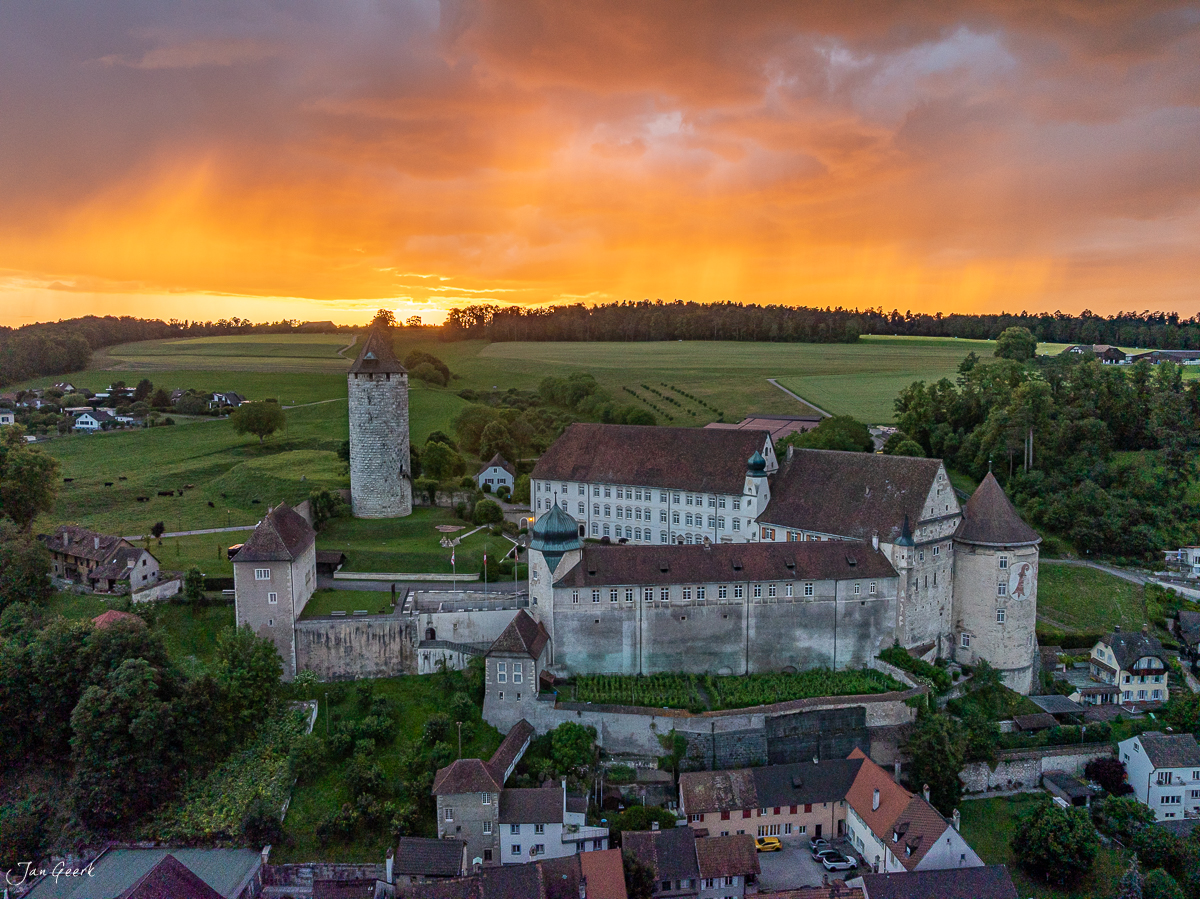 Luftaufnahme der Abtei Porrentruy mit Schlossturm und Burganlage in goldener Abenddimmung, Jura Schweiz – Jan Geerk Fotograf Basel