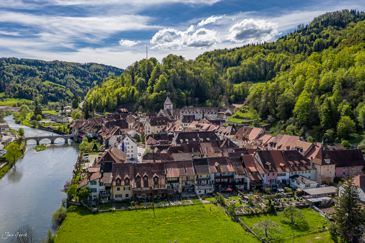 Luftaufnahme der Altstadt Saint-Ursanne mit Fluss Doubs im Frühling, umgeben von grünen Wäldern des Jura, Schweiz – Jan Geerk Fotograf Basel