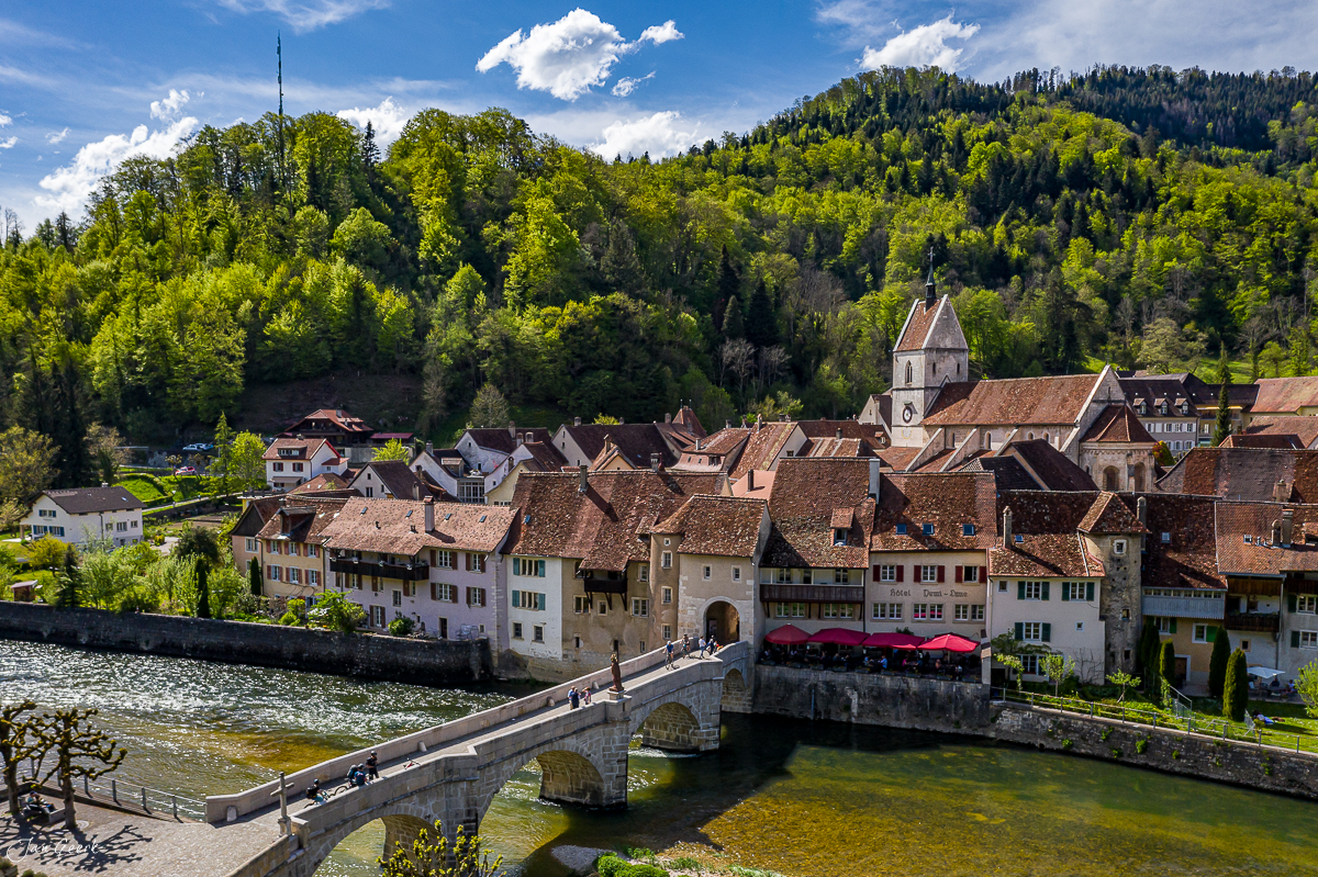 Luftaufnahme des malerischen Dorfes Ursanne mit Doubs-Fluss, Steinbrücke und Kirche im Frühling, Jura, Schweiz – Jan Geerk Fotograf Basel
