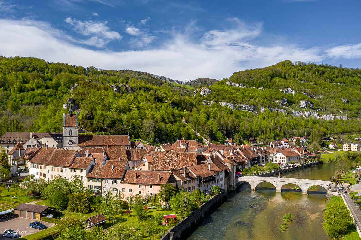 Luftaufnahme Dorf mit Kirche Fluss und bewaldete Jurahügel Frühling Schweiz Jan Geerk Fotograf Basel