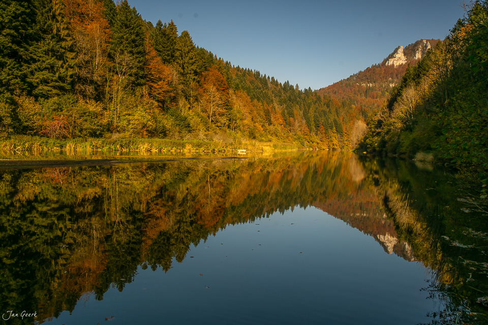 Spiegelglatte Seefläche mit Herbstwald und Felsklippen im Jura Schweiz – Jan Geerk Fotograf Basel