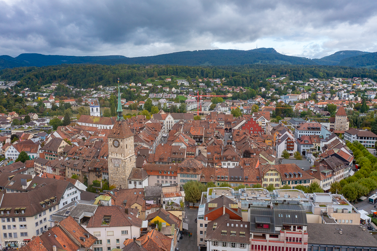 Luftaufnahme der Altstadt Aarau mit Kirchtürmen, Ziegeldächern und bewaldeten Hügeln im Hintergrund, Schweiz – Jan Geerk Fotograf Basel